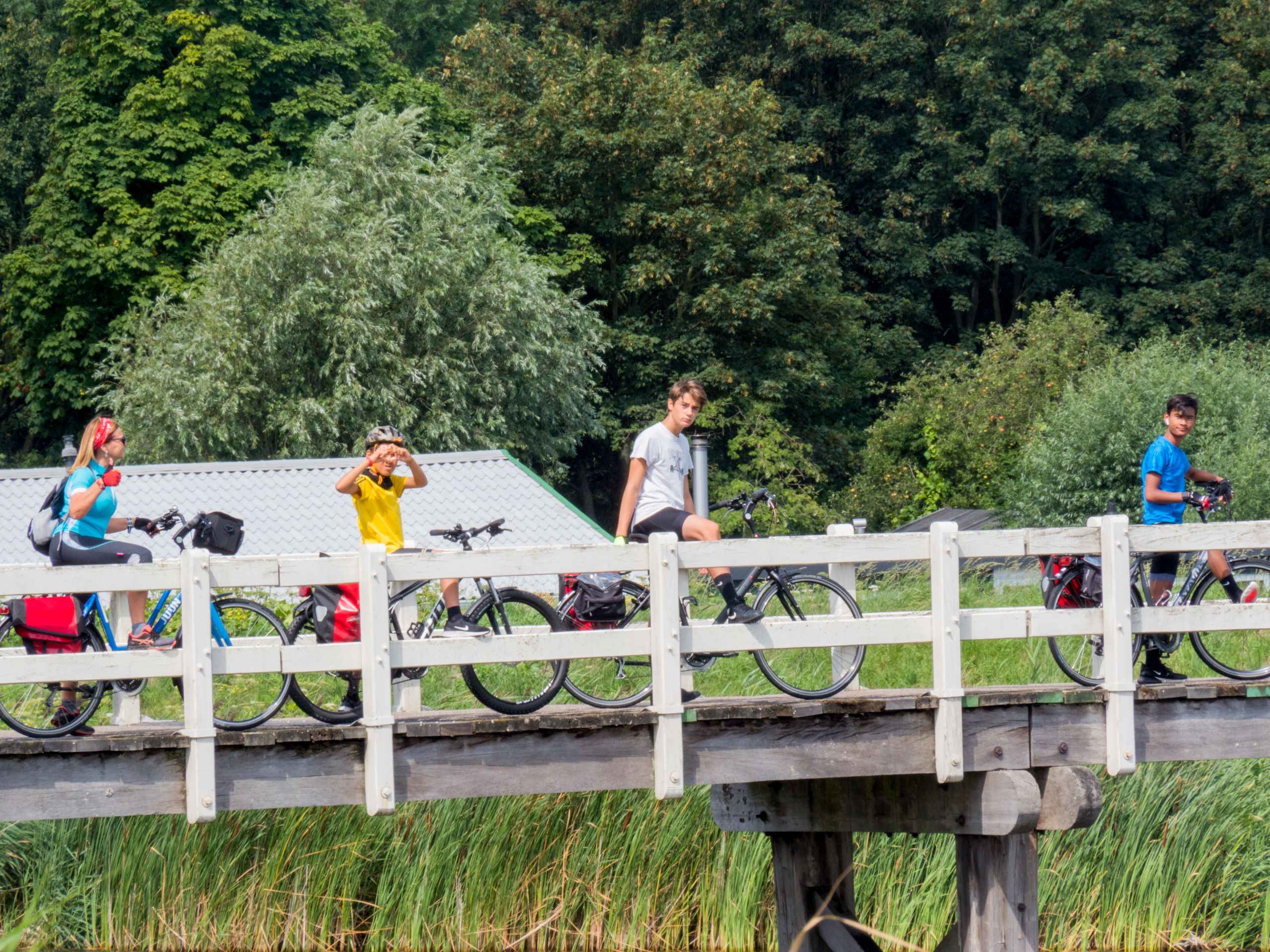Ciclisti sopra una passerella di legno sopra un fiume nel Parco del Delta del Po.